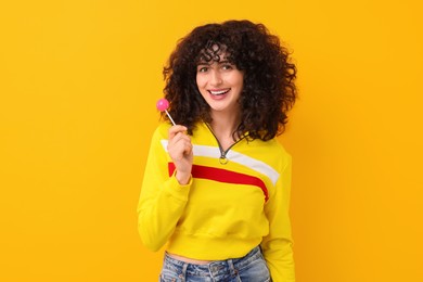 Beautiful woman with lollipop on yellow background