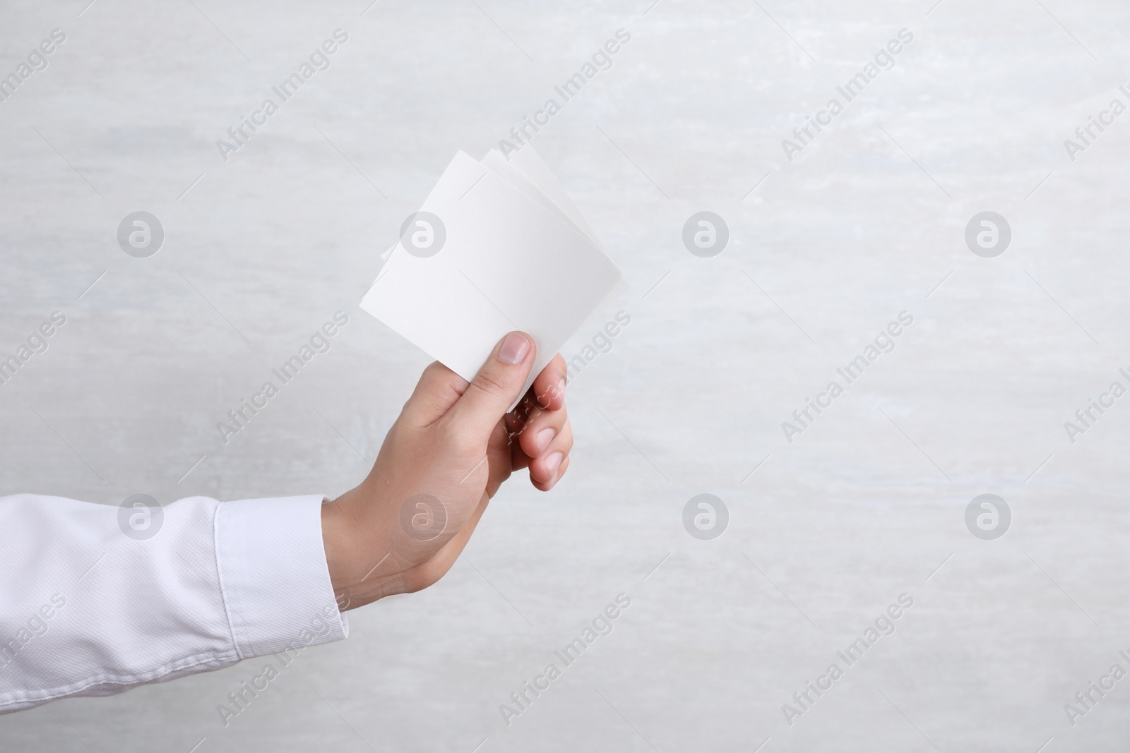 Photo of Man holding blank memory note papers on light background. Mock up for design