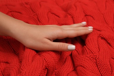 Photo of Woman touching soft red knitted fabric, closeup