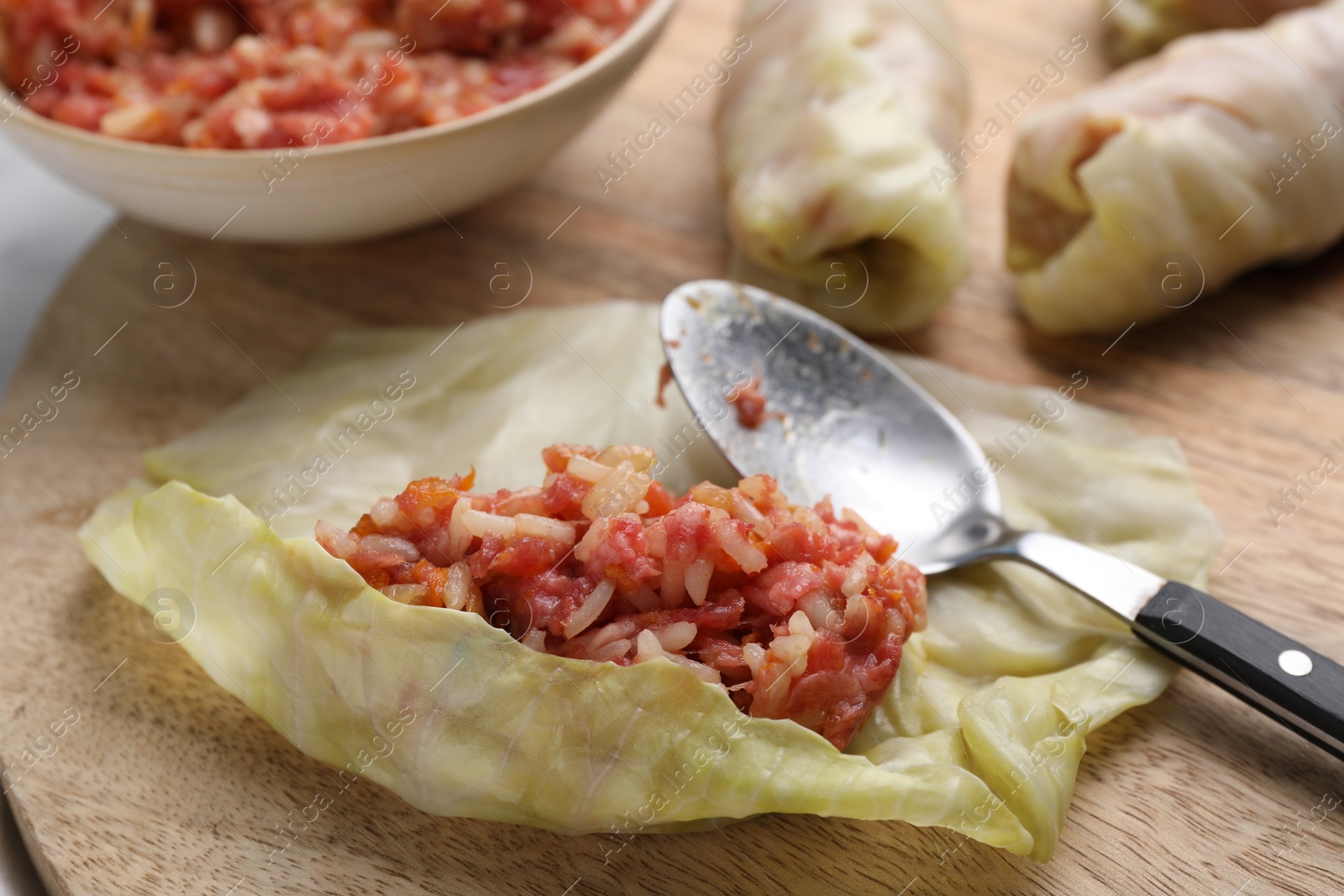 Photo of Preparing stuffed cabbage rolls on wooden board, closeup