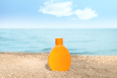Photo of Bottle of sun protection body cream on beach, space for design
