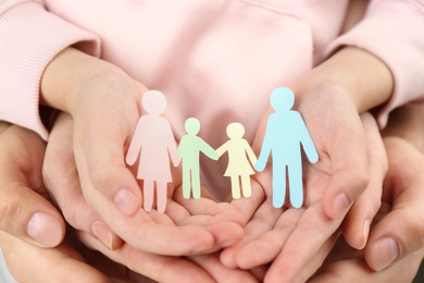 Photo of Parents and kid holding paper cutout of family in hands, closeup