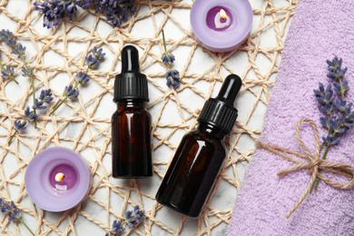 Flat lay composition with lavender flowers and natural essential oil on white marble table