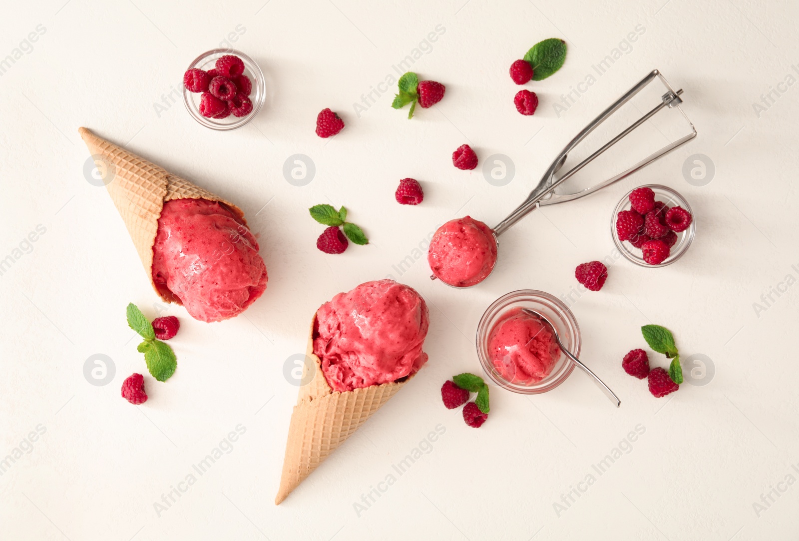 Photo of Flat lay composition with delicious pink ice cream in wafer cones and raspberries on white table