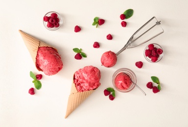 Photo of Flat lay composition with delicious pink ice cream in wafer cones and raspberries on white table