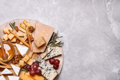 Photo of Cheese plate with honey, grapes and nuts on light grey marble table, top view. Space for text