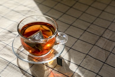 Photo of Tea bag in glass cup on table. Space for text