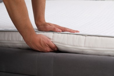 Man putting soft mattress on bed, closeup