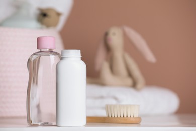 Bottles of baby cosmetic products and hair brush on white table. Space for text