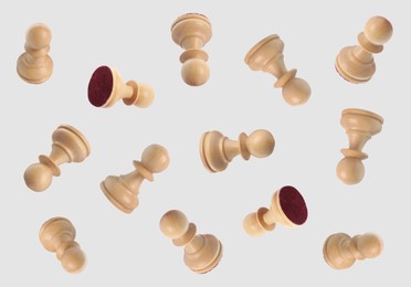 Image of Wooden chess pawns falling on light grey background