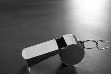 Photo of Referee equipment. Metal whistle on grey table, closeup and space for text