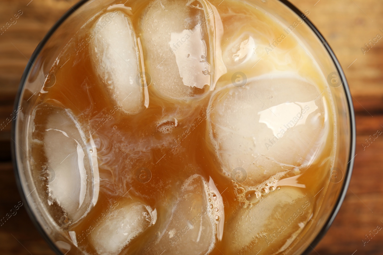 Photo of Coffee with milk and ice cubes in glass, top view