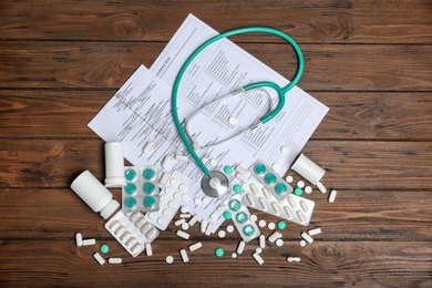 Flat lay composition with stethoscope and pills on wooden background. Cardiology service