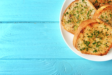 Photo of Slices of toasted bread with garlic and herbs on blue wooden table, top view. Space for text