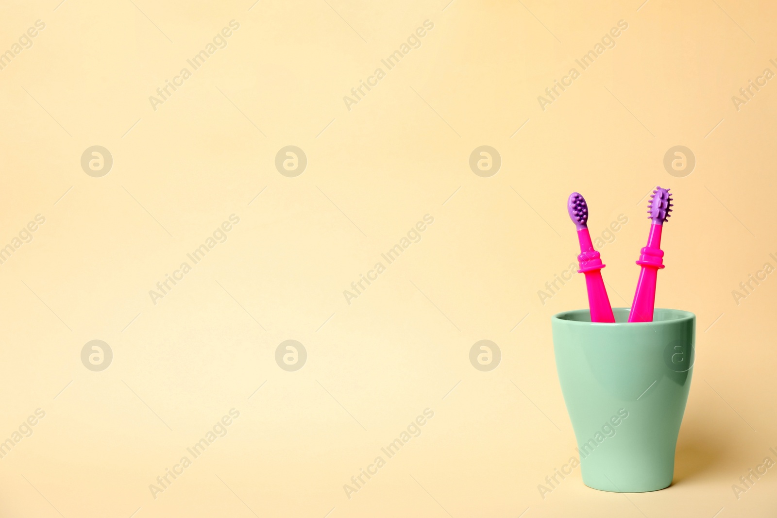 Photo of Baby toothbrushes in holder and space for text on color background