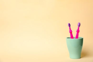 Photo of Baby toothbrushes in holder and space for text on color background