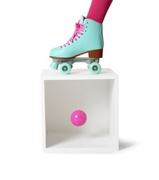 Photo of Woman wearing vintage roller skate and storage cube with ball on white background, closeup