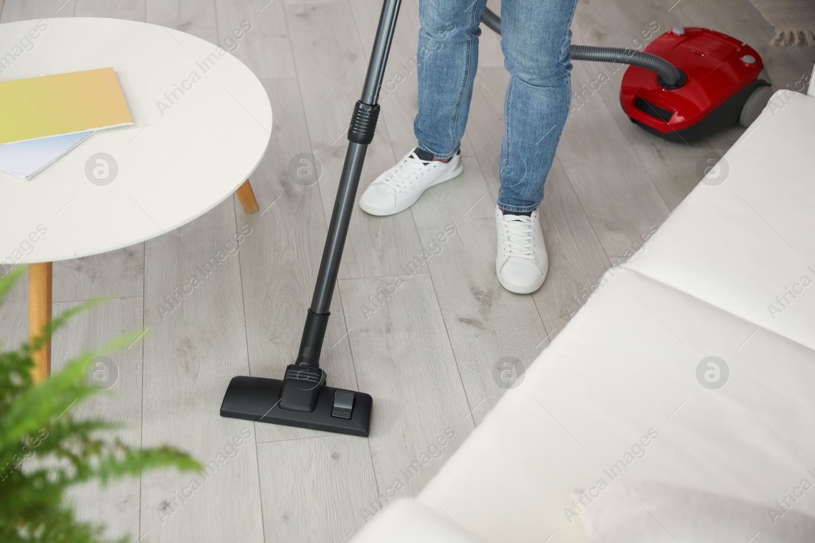 Photo of Young man using vacuum cleaner at home, closeup