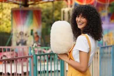 Photo of Smiling woman with cotton candy at funfair. Space for text