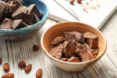 Bowl with pieces of delicious dark chocolate on wooden table