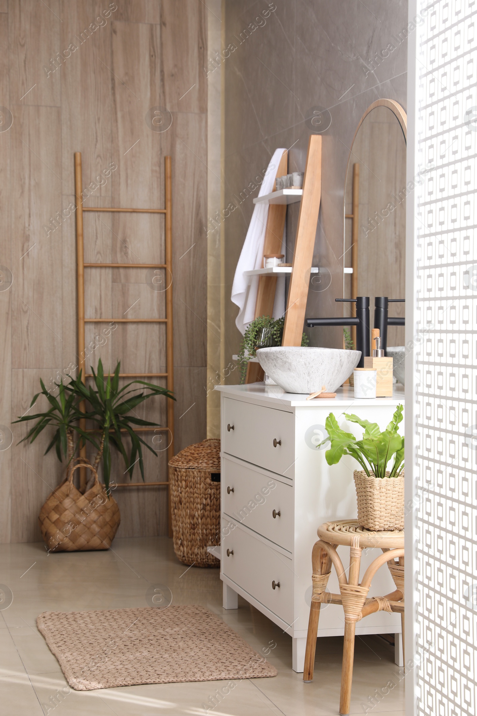 Photo of Chest of drawers with sink and beautiful green houseplants in bathroom. Interior design