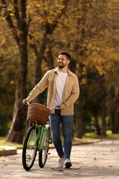 Photo of Young man with bicycle in autumn park, space for text