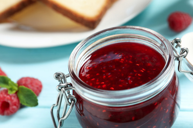 Sweet raspberry jam for breakfast on turquoise table, closeup