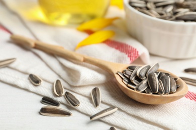 Photo of Organic sunflower seeds in spoon on table, closeup