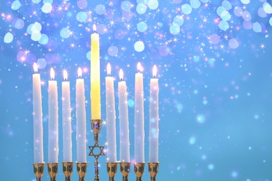 Image of Hanukkah celebration. Menorah with burning candles on light blue background with blurred lights, closeup. Space for text