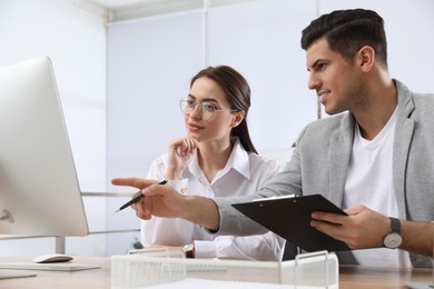 Photo of Businessman helping intern with work in office