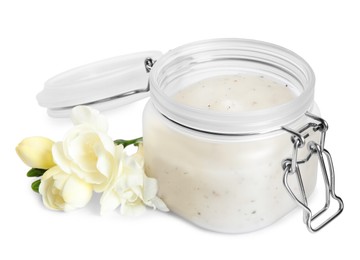 Photo of Jar of exfoliating salt scrub and freesia flowers on white background