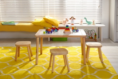 Wooden table and stools in baby room interior