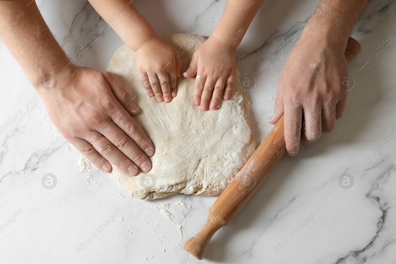 Photo of Father and child making dough at white table, top view