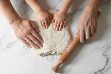 Photo of Father and child making dough at white table, top view