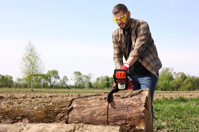 Man sawing wooden log on sunny day