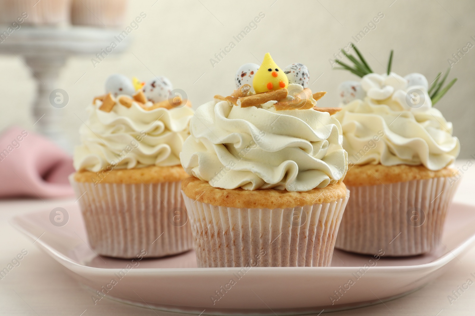 Photo of Tasty Easter cupcakes with vanilla cream on light table