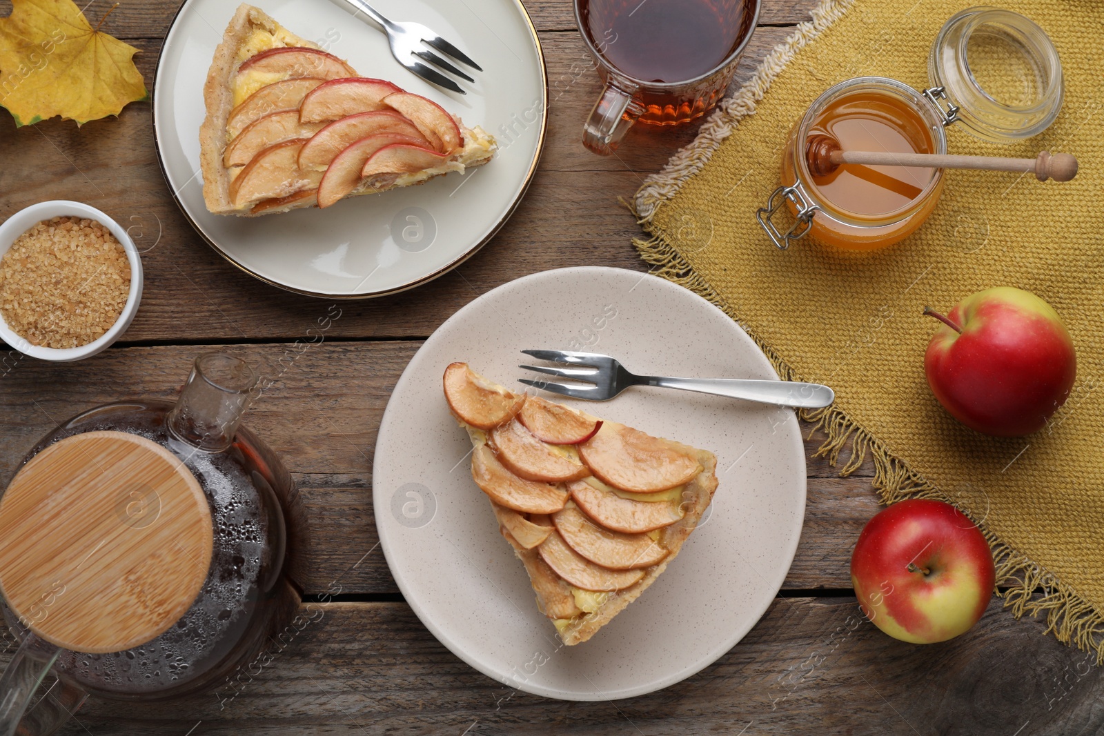 Photo of Freshly baked delicious apple pie served on wooden table, flat lay