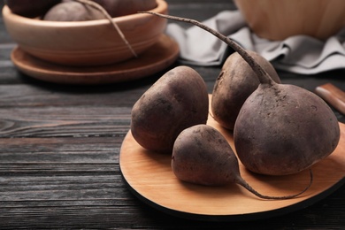 Wooden board with ripe beets on table