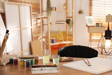 Paints and tools on wooden table in art studio