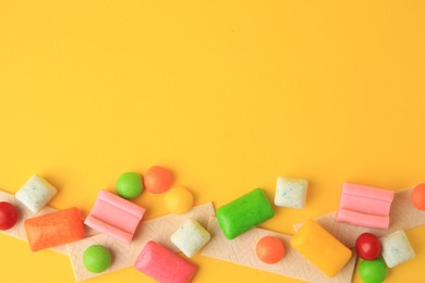 Photo of Many different chewing gums on yellow background, flat lay. Space for text