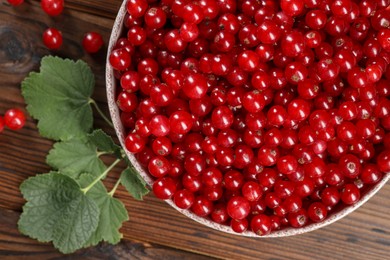 Ripe red currants and leaves on wooden table, flat lay
