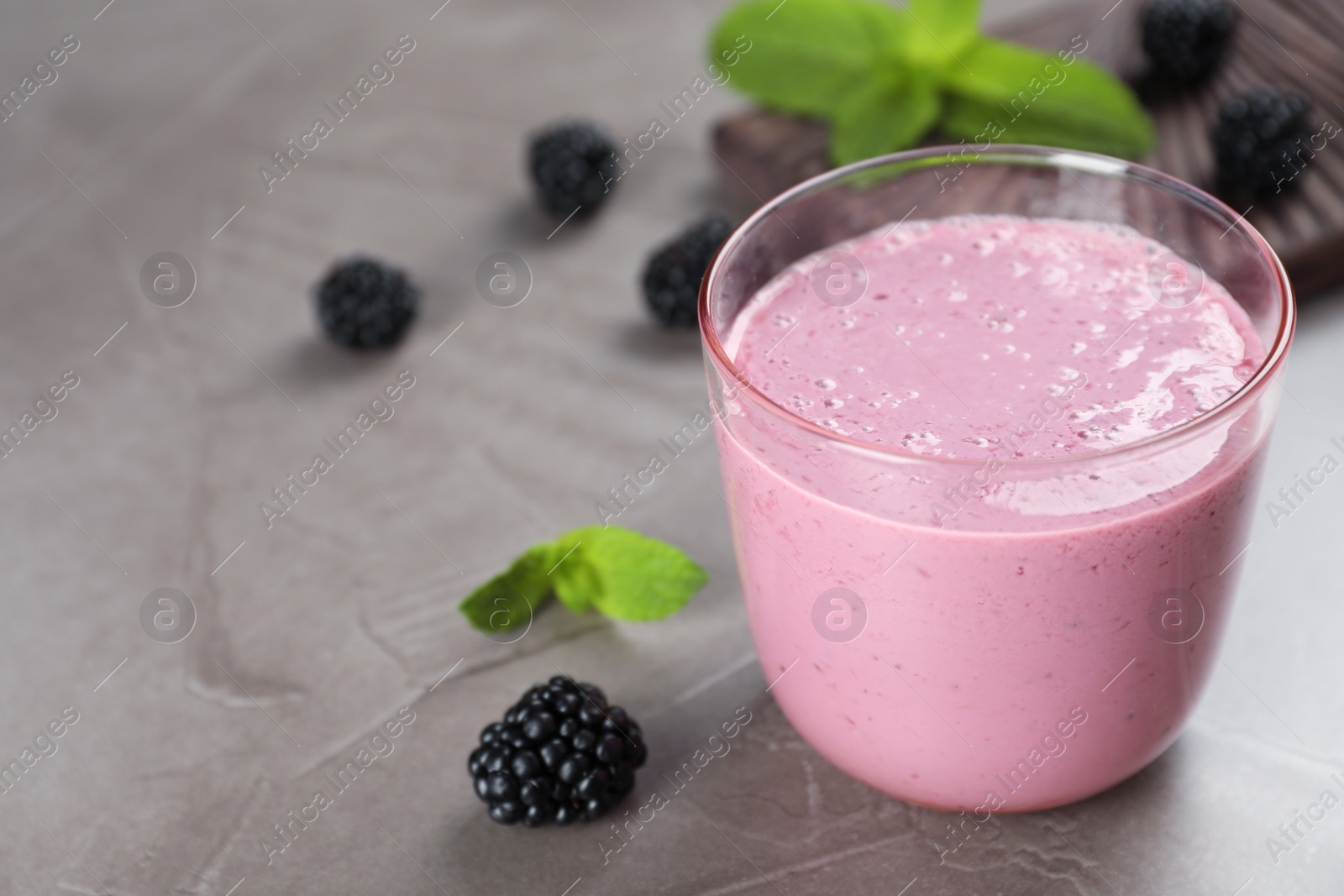 Photo of Glass with blackberry yogurt smoothie on grey table