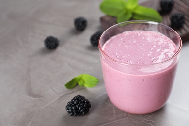 Photo of Glass with blackberry yogurt smoothie on grey table