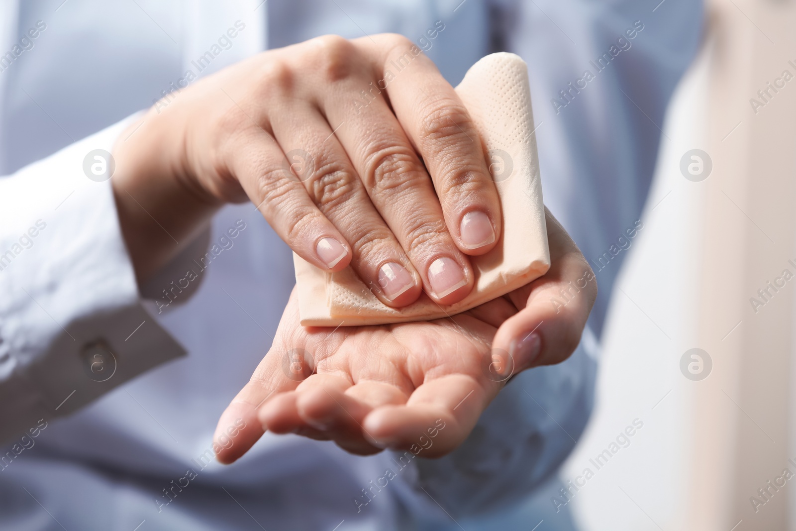 Photo of Woman cleaning hands with paper napkin, closeup