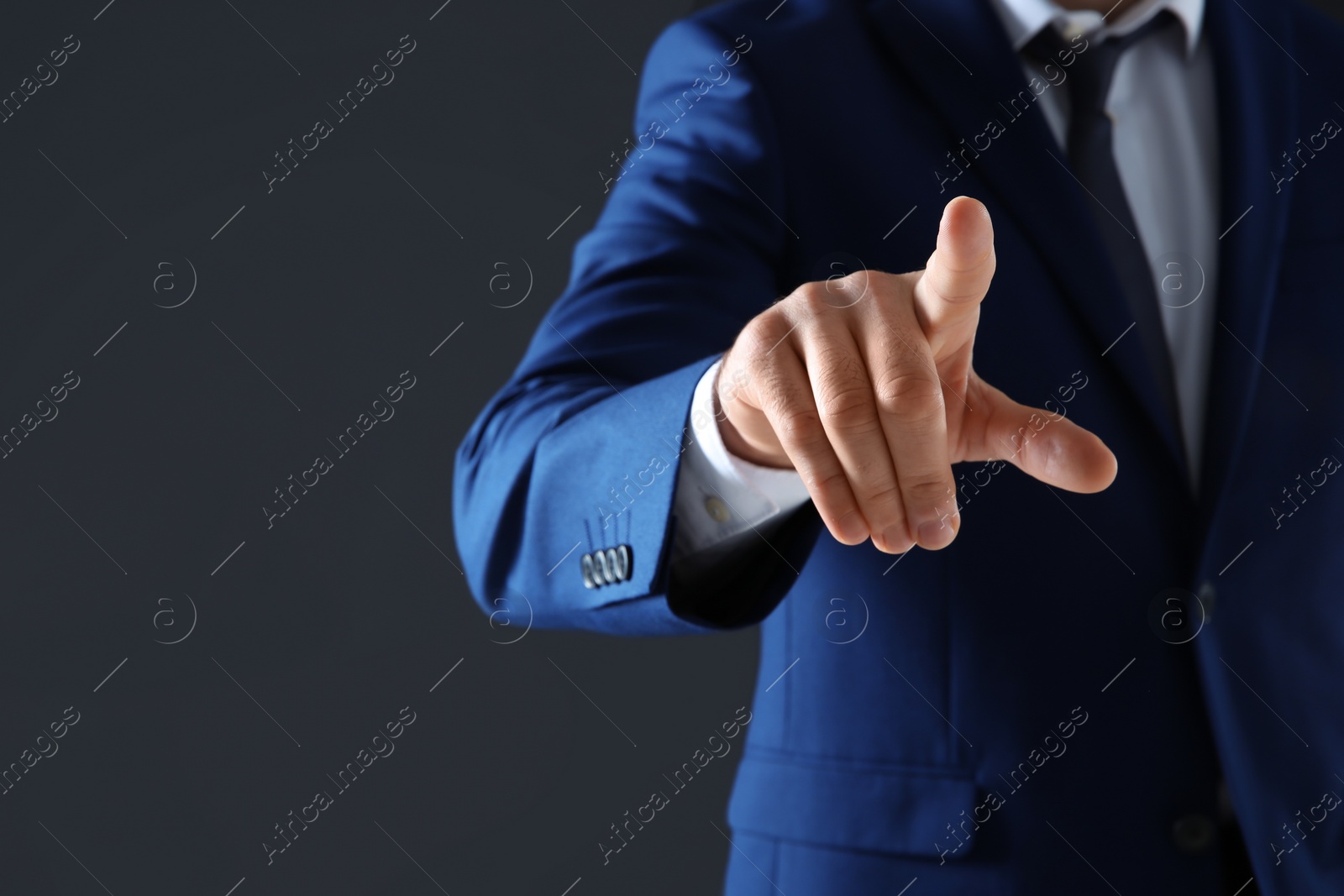 Photo of Businessman touching empty virtual screen against dark background, focus on hand