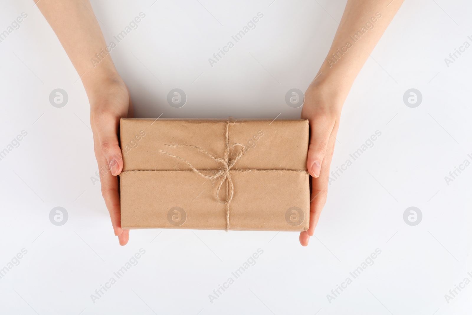 Photo of Woman holding parcel wrapped in kraft paper on white background, top view