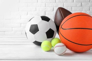 Photo of Set of different sport balls on white wooden table. Space for text