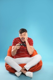 Emotional man playing video games with controller on color background. Space for text