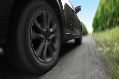 Image of Black car driving on road outdoors, closeup with motion blur effect. Space for text