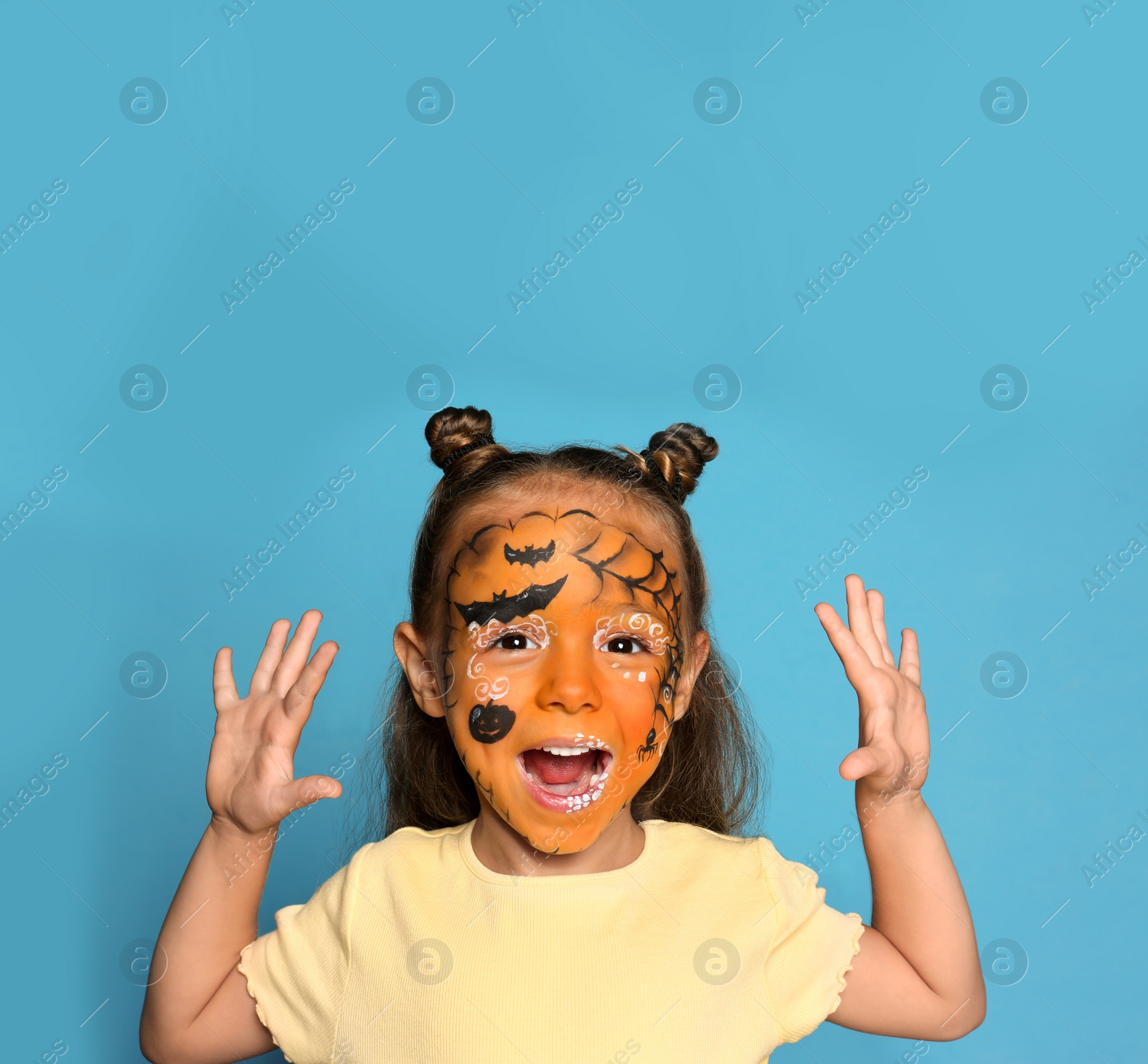 Photo of Cute little girl with face painting on blue background